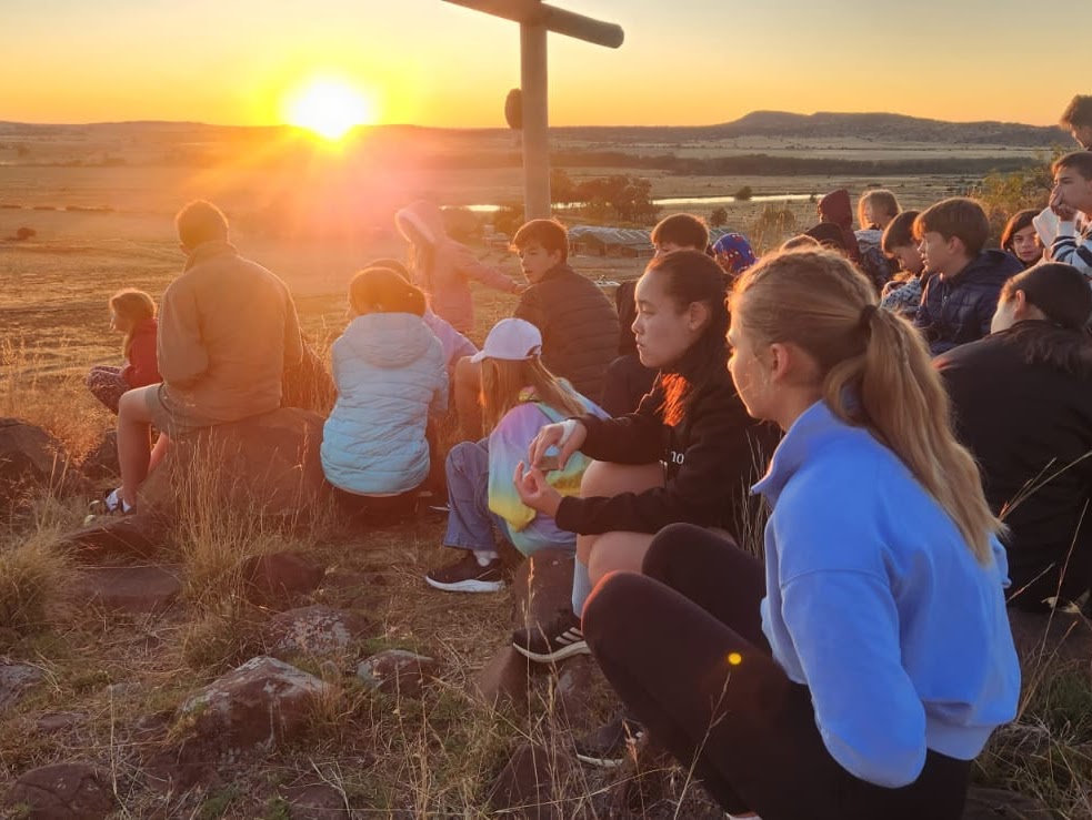 Learners sitting together at camp during sunset.